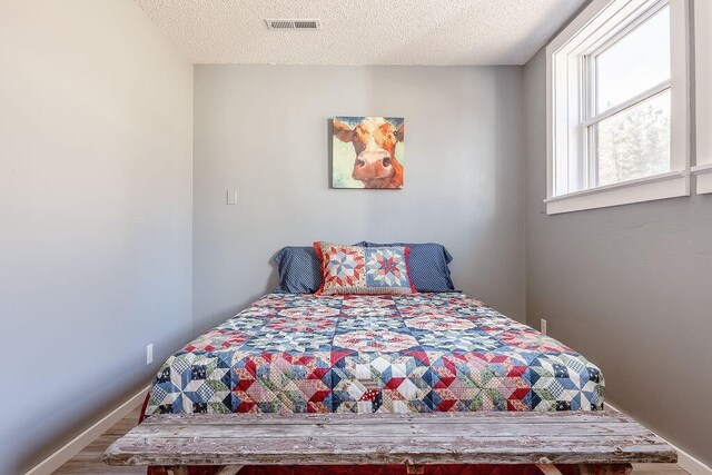 bedroom with a textured ceiling and wood-type flooring