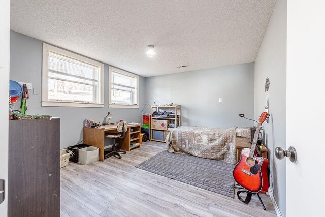 bedroom featuring light hardwood / wood-style floors and a textured ceiling