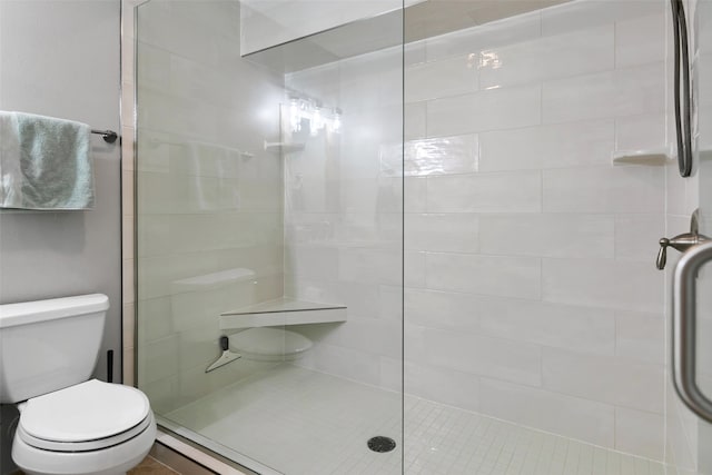 bathroom with a shower with shower door and toilet