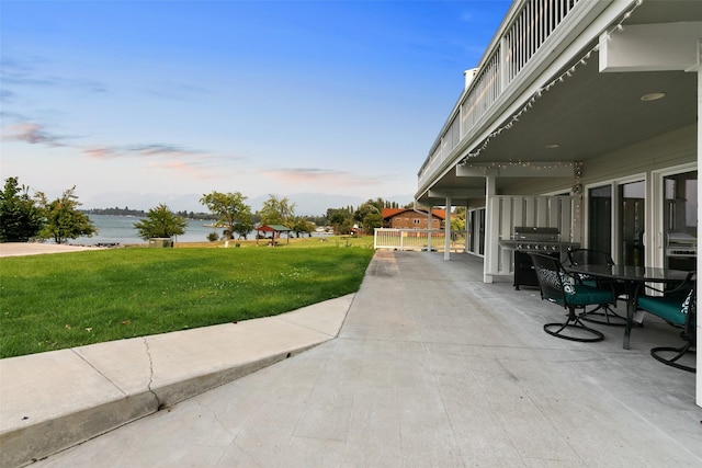 50300 US Highway 93 Unit B1/32, Polson, MT 59860 - patio terrace at dusk with a yard, a water view, a patio area, a grill, and outdoor dining space