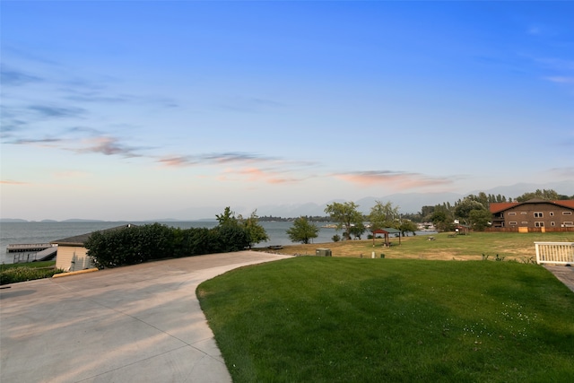 yard at dusk featuring a water view