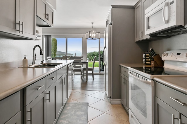 kitchen with light tile flooring, a notable chandelier, stainless steel appliances, decorative light fixtures, and sink