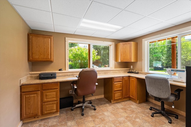 office space featuring a paneled ceiling and built in desk