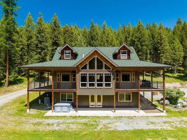 rear view of house with a patio area, cooling unit, and a hot tub