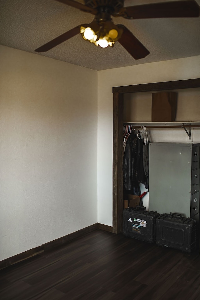 unfurnished bedroom with ceiling fan, a textured ceiling, dark wood-type flooring, and a closet