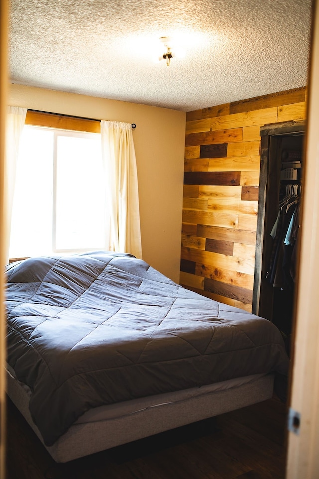 bedroom featuring wooden walls and a textured ceiling