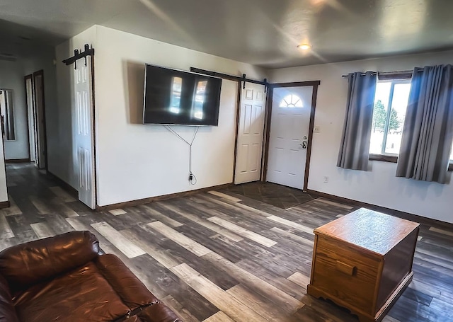 unfurnished living room with a barn door and dark hardwood / wood-style flooring