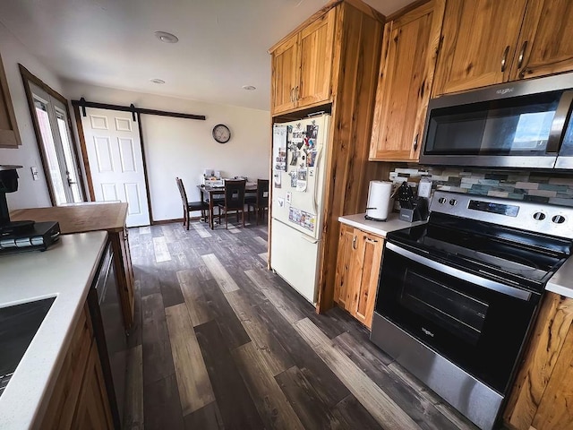 405 S Cherry St, Townsend, MT 59644 - kitchen featuring appliances with stainless steel finishes, a barn door, brown cabinetry, and dark wood-style floors