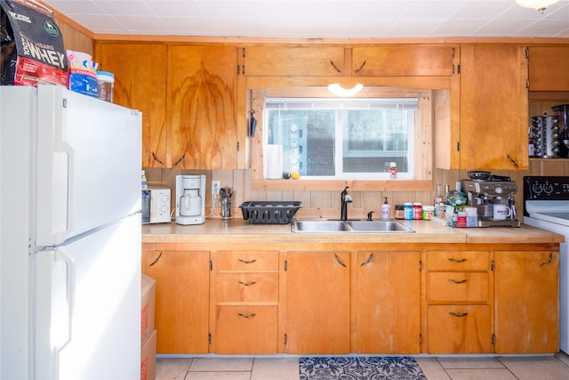 kitchen featuring washer / dryer, white refrigerator, light tile floors, and sink