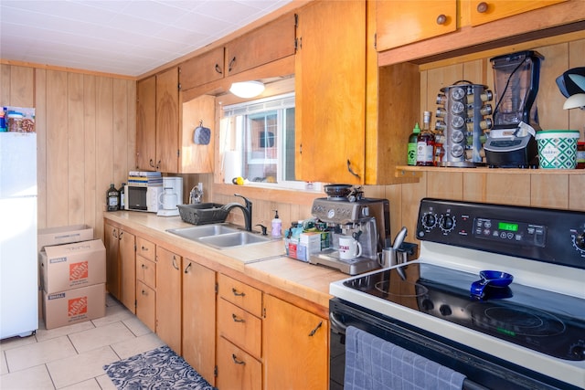 kitchen featuring light tile flooring, white appliances, wooden walls, and sink