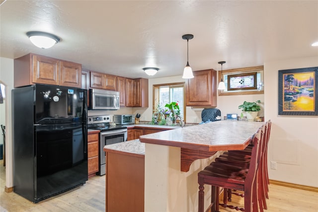 707 W Desta St, Hamilton, MT 59840 - kitchen with kitchen peninsula, hanging light fixtures, a breakfast bar, light wood-type flooring, and stainless steel appliances
