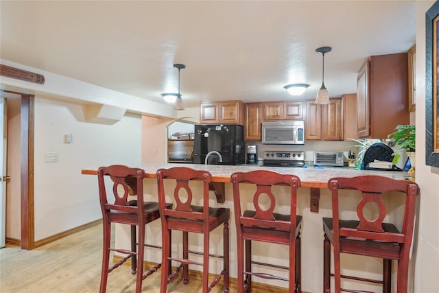 707 W Desta St, Hamilton, MT 59840 - kitchen featuring range, decorative light fixtures, a breakfast bar, light hardwood / wood-style floors, and black fridge