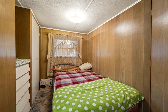 bedroom featuring wood walls, a textured ceiling, and dark carpet