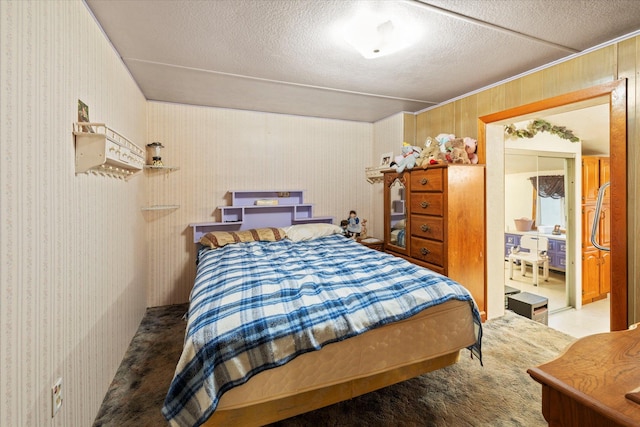 bedroom featuring carpet flooring, wooden walls, and a textured ceiling