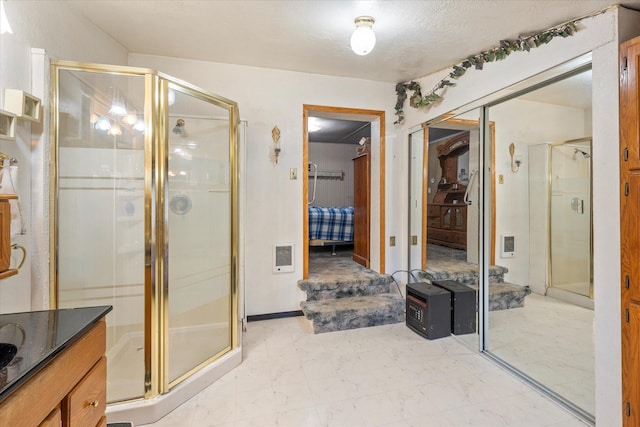 bathroom featuring heating unit, a shower with door, and vanity