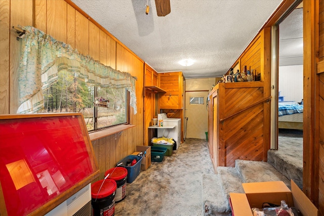 interior space with light carpet, a textured ceiling, ceiling fan, and wooden walls