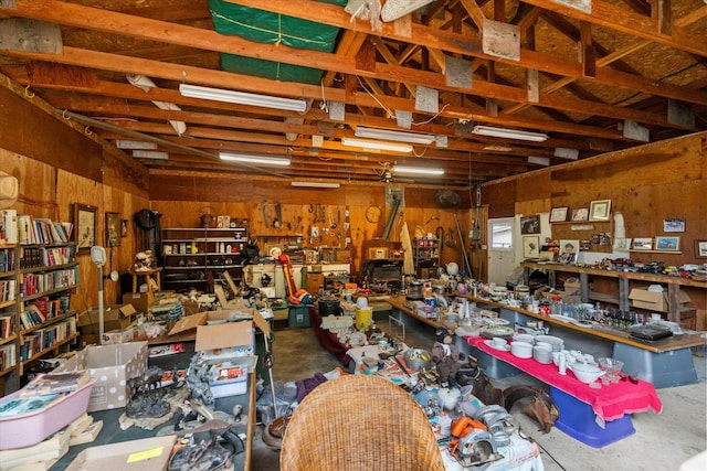 miscellaneous room with a workshop area, wooden walls, and concrete floors