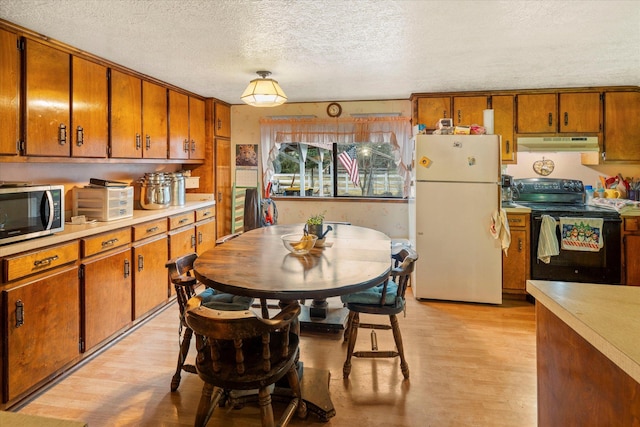 kitchen featuring pendant lighting, white refrigerator, electric range, a textured ceiling, and light hardwood / wood-style floors