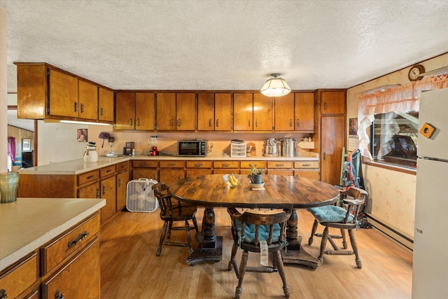 kitchen featuring white refrigerator, light wood-type flooring, a textured ceiling, and a baseboard radiator