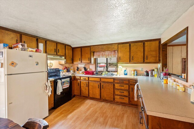 kitchen with light hardwood / wood-style floors, a textured ceiling, sink, white fridge, and black electric range oven