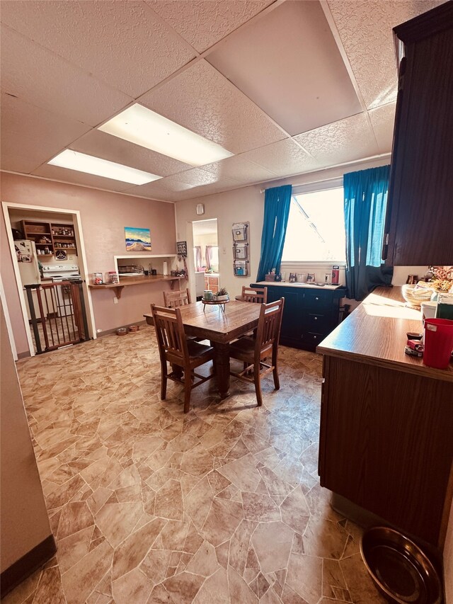 tiled dining room with a drop ceiling