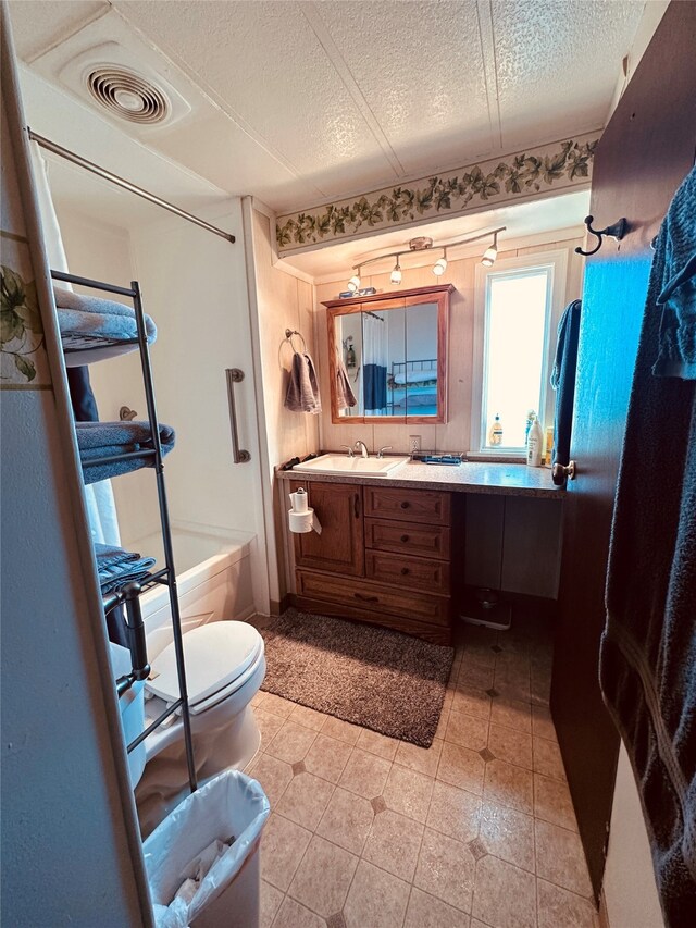 full bathroom with toilet, vanity, a textured ceiling, washtub / shower combination, and tile floors