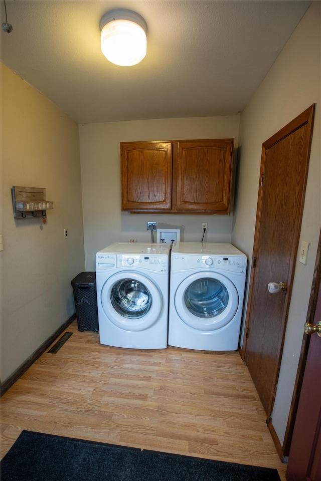 laundry area featuring light hardwood / wood-style flooring, washing machine and dryer, cabinets, and hookup for a washing machine