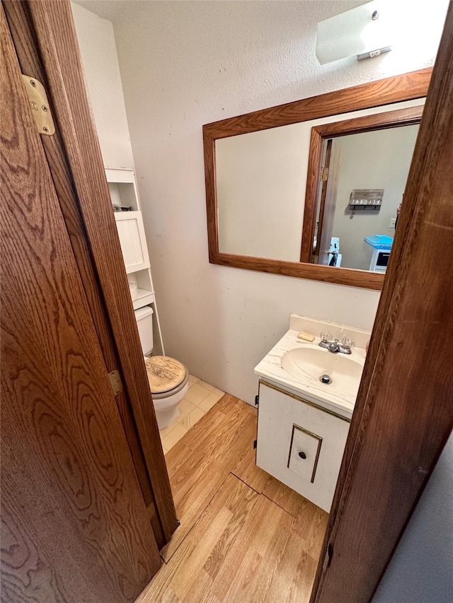 bathroom with toilet, hardwood / wood-style floors, and vanity