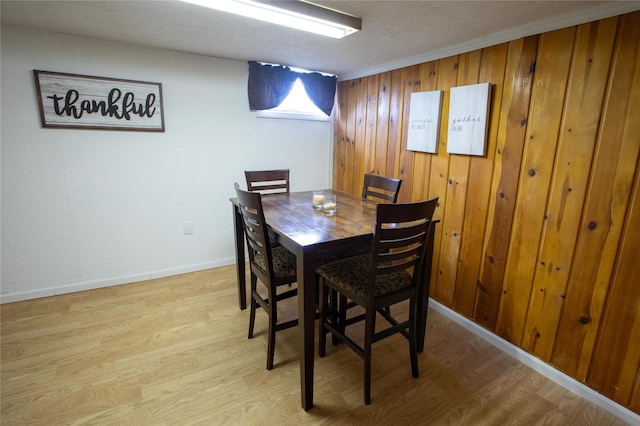 dining area featuring light hardwood / wood-style floors and wood walls