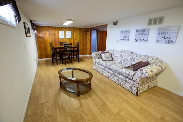 living room with wooden walls and light hardwood / wood-style flooring