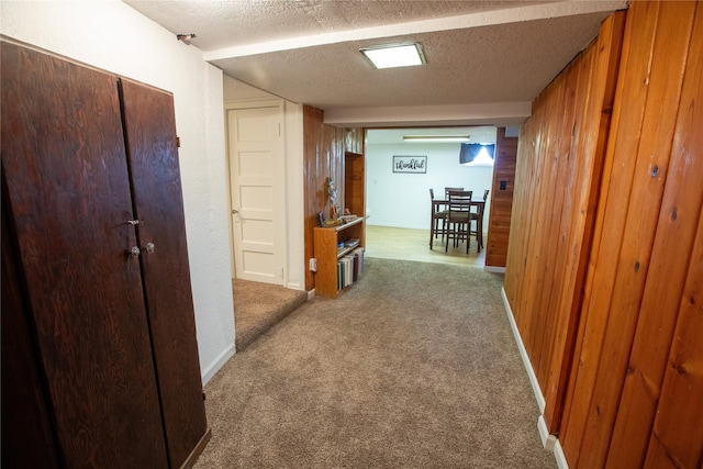 corridor featuring wooden walls, carpet floors, and a textured ceiling