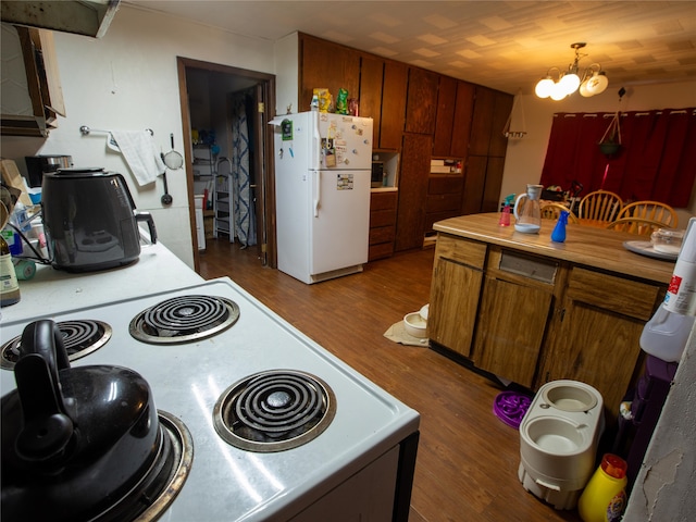 kitchen with hardwood / wood-style floors, decorative light fixtures, white fridge, an inviting chandelier, and stove