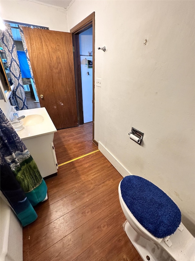 interior space with vanity, toilet, hardwood / wood-style flooring, and ornamental molding