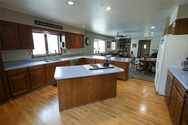 kitchen featuring kitchen peninsula, ceiling fan, white appliances, sink, and a kitchen island