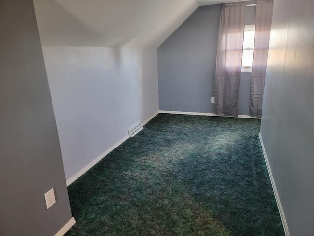 bonus room with dark carpet and vaulted ceiling