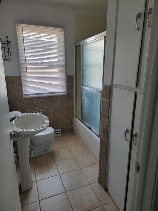 bathroom featuring bath / shower combo with glass door, tile walls, tile patterned flooring, and toilet