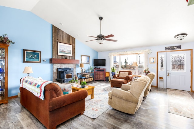 living room featuring hardwood / wood-style floors, vaulted ceiling, a wood stove, and ceiling fan