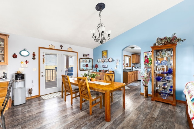 dining space with french doors, dark wood-type flooring, an inviting chandelier, and lofted ceiling