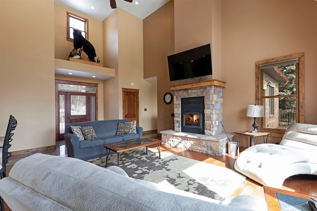 living room with wood-type flooring, a fireplace, and a high ceiling