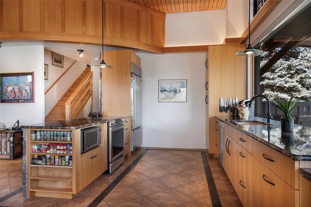 kitchen with appliances with stainless steel finishes, sink, dark stone counters, pendant lighting, and light brown cabinets