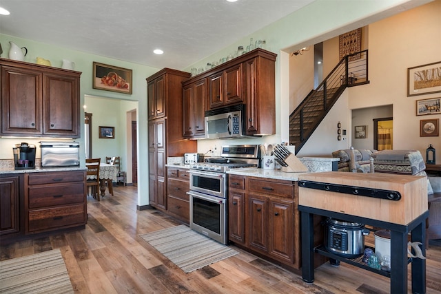 165 Jewel View Dr, Columbia Falls, MT 59912 - kitchen with appliances with stainless steel finishes, recessed lighting, light wood-style flooring, dark brown cabinets, and light stone countertops
