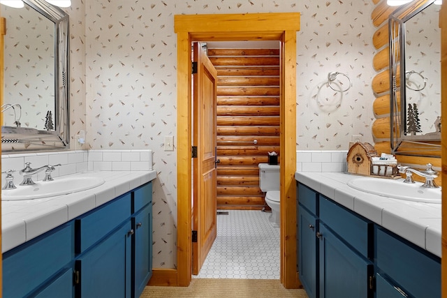 bathroom featuring tile flooring, rustic walls, toilet, and vanity