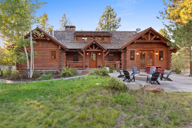 770 Pallo Trl, Hamilton, MT 59840 - rear view of house featuring an outdoor fire pit, log siding, a chimney, a lawn, and a patio area