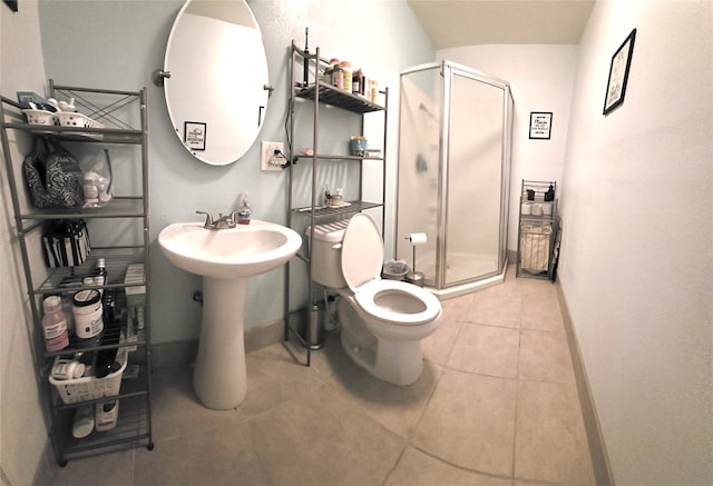 bathroom featuring a shower with shower door, toilet, and tile patterned floors