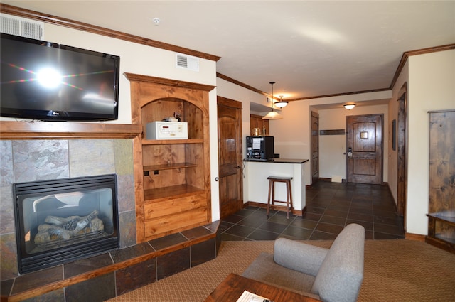 living room with dark tile flooring, crown molding, and a tile fireplace