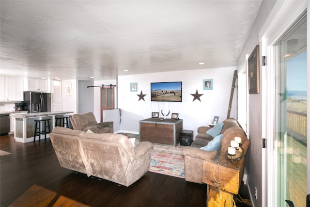 living room featuring a barn door and dark wood-type flooring