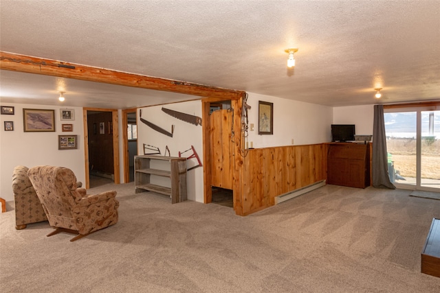 basement with a baseboard heating unit, a textured ceiling, and light carpet