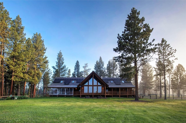 back of house with solar panels, a deck, and a yard