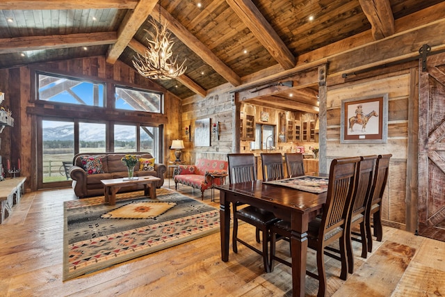 dining space with beamed ceiling, hardwood / wood-style flooring, a barn door, an inviting chandelier, and wooden ceiling