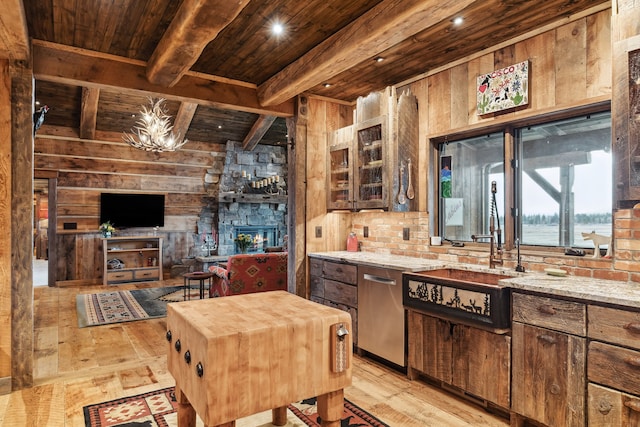 kitchen with wood ceiling, a stone fireplace, wood walls, light stone countertops, and light wood-type flooring